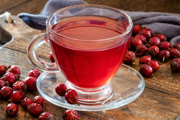 A cup of herbal tea with dried rose hips on a table