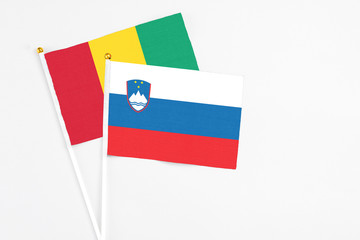 Slovenia and Guinea stick flags on white background. High quality fabric, miniature national flag. Peaceful global concept.White floor for copy space.