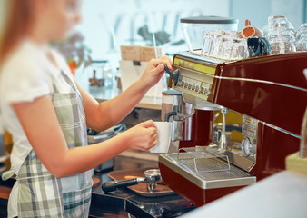 Seller using a coffee machine pours coffee.