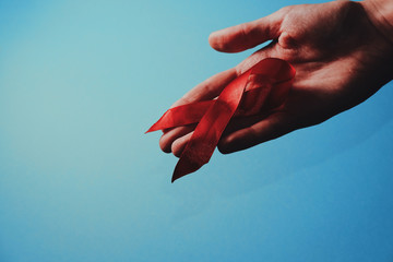 healthcare and medicine concept - female hand holding red AIDS awareness ribbon