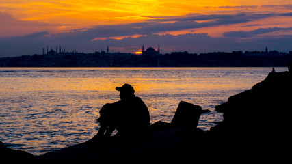 Naklejka na ściany i meble silhouette of fisherman at sunset