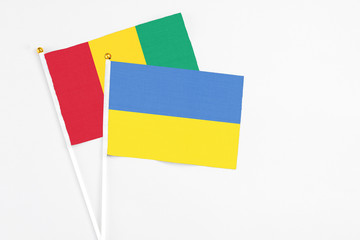 Ukraine and Guinea stick flags on white background. High quality fabric, miniature national flag. Peaceful global concept.White floor for copy space.