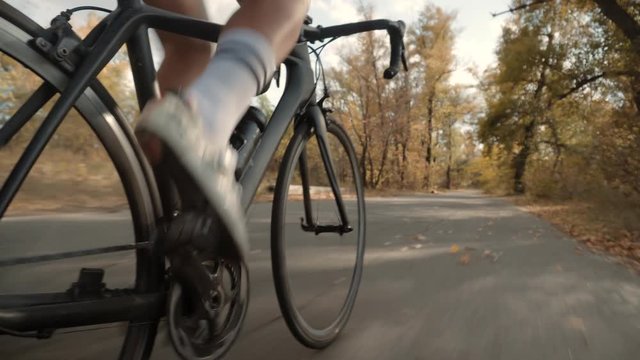 Cyclist Pedaling On City Park At Autumn.Cycling Athlete At Sunset Fall On City.Gear System Road Bicycle And Bike Wheel Rotation.Cyclist Twists Pedals And Riding On Road Bicycle.Sport Concept	