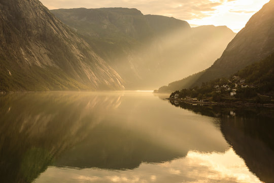 Shafts of light enter misty, beautiful Eidfjord, fjord reflections, Hardangerfjord, Norwegian Western Fjords