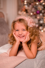 Obraz na płótnie Canvas little blonde girl in bed next to Christmas tree. christmas eve