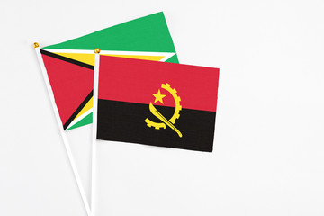 Angola and Guyana stick flags on white background. High quality fabric, miniature national flag. Peaceful global concept.White floor for copy space.