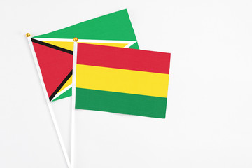 Bolivia and Guyana stick flags on white background. High quality fabric, miniature national flag. Peaceful global concept.White floor for copy space.