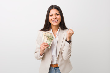 Young arab business woman holding dollars cheering carefree and excited. Victory concept.