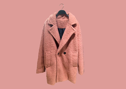Fashionable Pink women Faux shearling coat on a hanger isolated on pink background.  Composition of clothes. Flat lay, top view, copy space. Winter clothes pattern. Ladies' Trench Coat. Pattern
