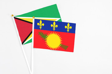 Guadeloupe and Guyana stick flags on white background. High quality fabric, miniature national flag. Peaceful global concept.White floor for copy space.