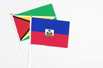 Haiti and Guyana stick flags on white background. High quality fabric, miniature national flag. Peaceful global concept.White floor for copy space.