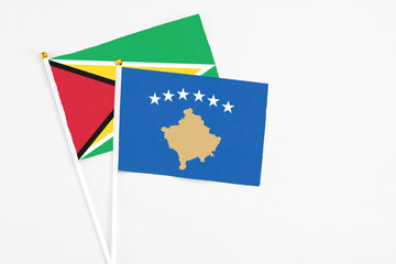 Kosovo and Guyana stick flags on white background. High quality fabric, miniature national flag. Peaceful global concept.White floor for copy space.
