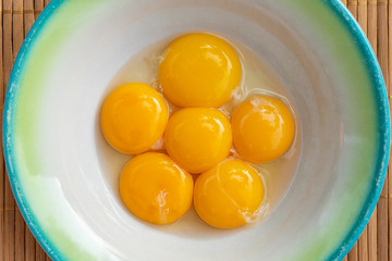 Chicken yolks lie in a white plate with a green border