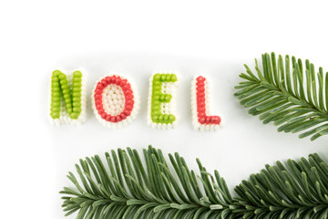 extreme macro close up of candy letters spell out NOEL with a pine branch isolated on white