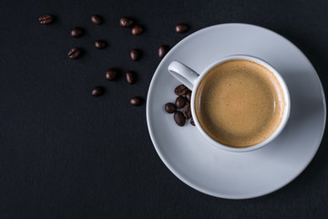 Top view of coffee cup on pile of coffee beans and cloth on wood dark background with copy space for write text concept