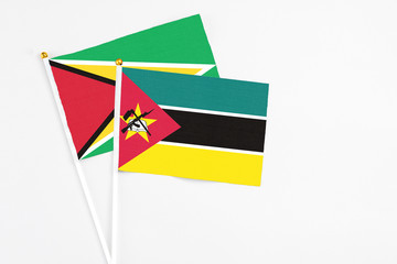 Mozambique and Guyana stick flags on white background. High quality fabric, miniature national flag. Peaceful global concept.White floor for copy space.
