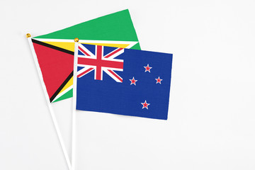 New Zealand and Guyana stick flags on white background. High quality fabric, miniature national flag. Peaceful global concept.White floor for copy space.