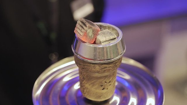 Man preparing hookah bowl and coald for smoking shisha. Hot embers for a hookah. Coconut Coals on Aluminum foil on Hookah Cup