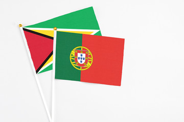 Portugal and Guyana stick flags on white background. High quality fabric, miniature national flag. Peaceful global concept.White floor for copy space.