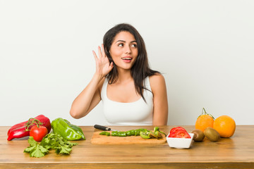 Young curvy woman preparing a healthy meal trying to listening a gossip.