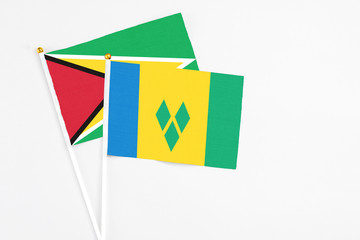 Saint Vincent And The Grenadines and Guyana stick flags on white background. High quality fabric, miniature national flag. Peaceful global concept.White floor for copy space.