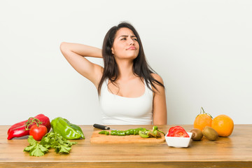 Young curvy woman preparing a healthy meal touching back of head, thinking and making a choice.