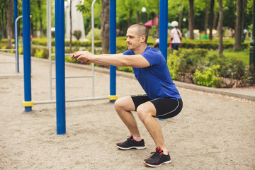 Man doing squats in the sports ground in park