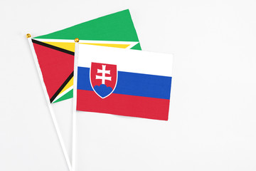 Slovakia and Guyana stick flags on white background. High quality fabric, miniature national flag. Peaceful global concept.White floor for copy space.