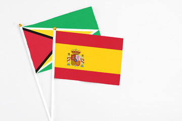 Spain and Guyana stick flags on white background. High quality fabric, miniature national flag. Peaceful global concept.White floor for copy space.