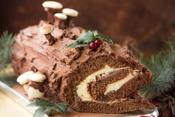 Chocolate yule log christmas cake on wooden background.
