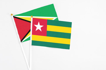 Togo and Guyana stick flags on white background. High quality fabric, miniature national flag. Peaceful global concept.White floor for copy space.