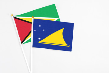 Tokelau and Guyana stick flags on white background. High quality fabric, miniature national flag. Peaceful global concept.White floor for copy space.