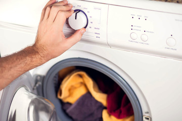 Man switches on the washing machine and choses washing mode