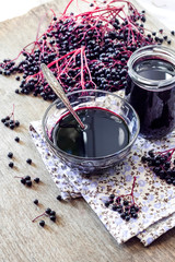 Homemade black elderberry syrup in glass bowl and jar