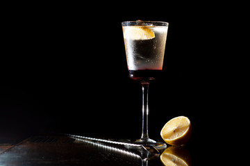 bartender makes a cocktail with champagne in a glass on a black background