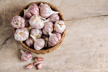 Garlic in a wicker basket on a wooden table background. Top view. Copy, empty space for text