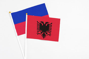 Albania and Haiti stick flags on white background. High quality fabric, miniature national flag. Peaceful global concept.White floor for copy space.