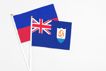 Anguilla and Haiti stick flags on white background. High quality fabric, miniature national flag. Peaceful global concept.White floor for copy space.