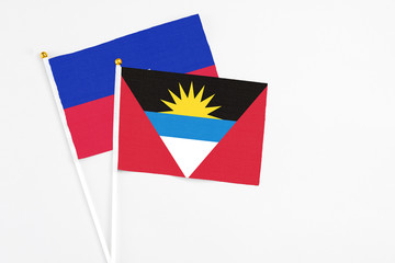 Antigua and Barbuda and Haiti stick flags on white background. High quality fabric, miniature national flag. Peaceful global concept.White floor for copy space.