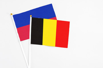 Belgium and Haiti stick flags on white background. High quality fabric, miniature national flag. Peaceful global concept.White floor for copy space.