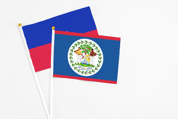 Belize and Haiti stick flags on white background. High quality fabric, miniature national flag. Peaceful global concept.White floor for copy space.