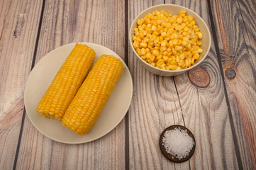 Two ears of boiled corn in a plate and coarse salt on the table. Healthy diet. Fitness diet. For a sweet treat.