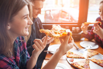 young girl eating a slice of pizza indoors, girl student gives pizza, close-up