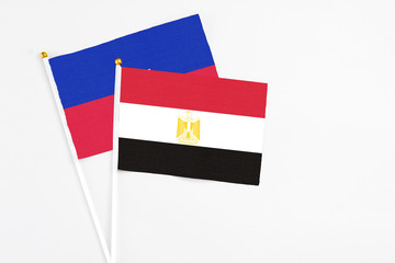 Egypt and Haiti stick flags on white background. High quality fabric, miniature national flag. Peaceful global concept.White floor for copy space.