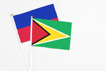 Guyana and Haiti stick flags on white background. High quality fabric, miniature national flag. Peaceful global concept.White floor for copy space.