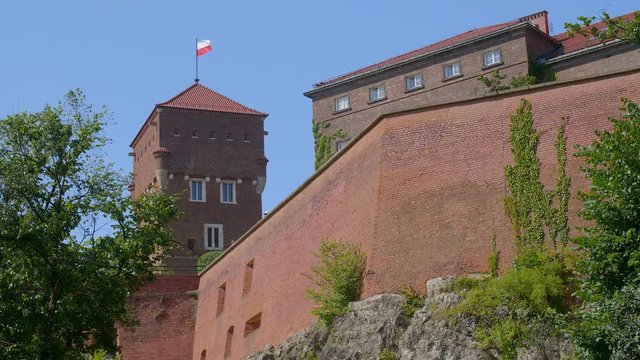 Walls and tower of Wawel castle on Krakow, Poland with Polish flag blowing in the wind.