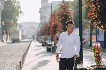 Obraz premium young stylish guy in a shirt walking down a European street on a sunny day