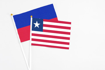 Liberia and Haiti stick flags on white background. High quality fabric, miniature national flag. Peaceful global concept.White floor for copy space.