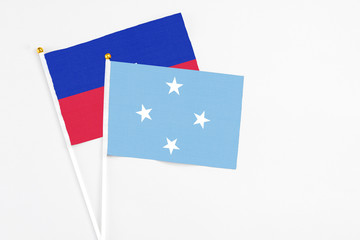 Micronesia and Haiti stick flags on white background. High quality fabric, miniature national flag. Peaceful global concept.White floor for copy space.