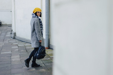 Attractive young girl in glasses in coat and yellow Beret freestyle walking